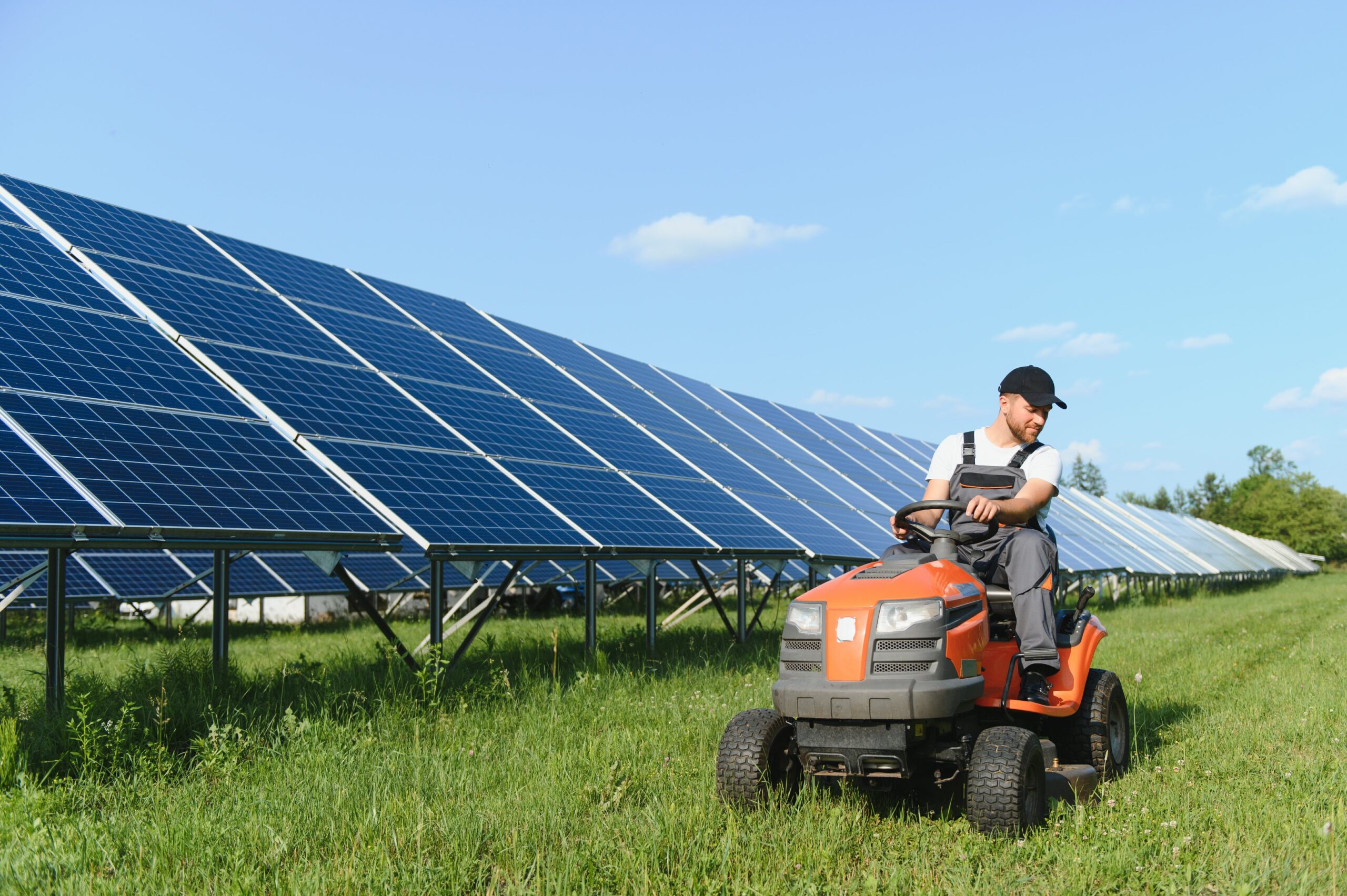 a-man-mows-the-grass-near-the-solar-panels-green-2023-11-28-02-27-19-utc-min